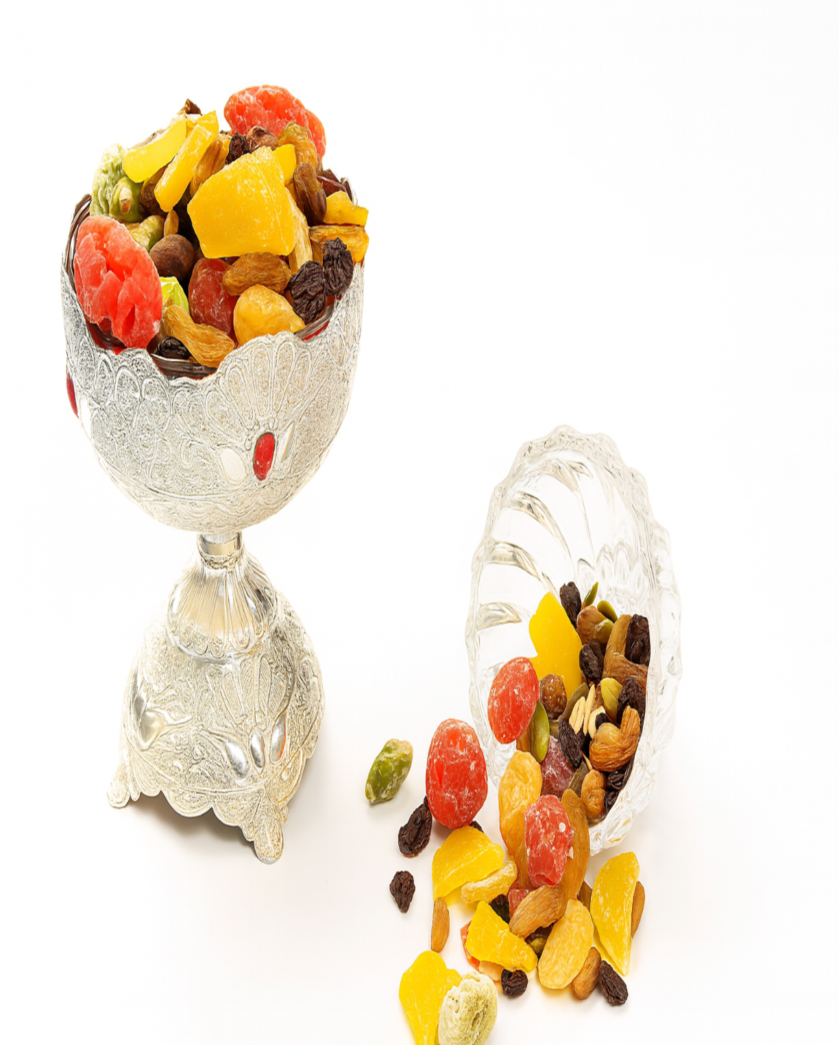 Decorative silver bowl filled with dried fruits on a white background